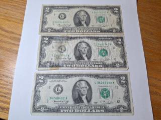 Three $2 bills, one is torn in half 