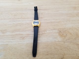 Gold colored Texas instruments watch, with black band
